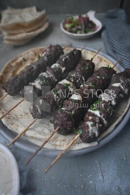 Dish with grilled kofta with tahini sauce on it