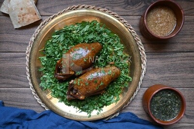 plate with stuffed pigeons beside soup and bread