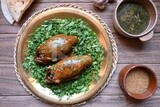 plate with stuffed pigeons beside soup and bread.