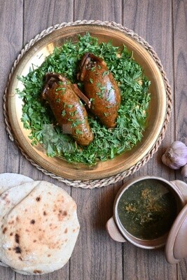 plate with stuffed pigeons beside soup and bread.
