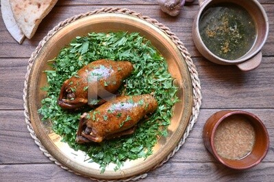 plate with stuffed pigeons beside soup and bread