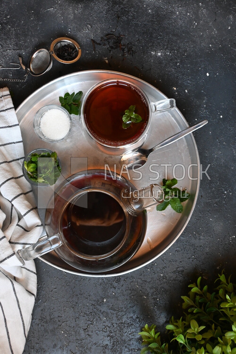 كوب من الشاى مع غلاية زجاج وسكر ونعناع على صينية