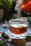 Glass kettle pouring tea from jug to cup of tea