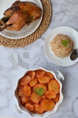 Potato tray sits beside a plate of rice and chicken