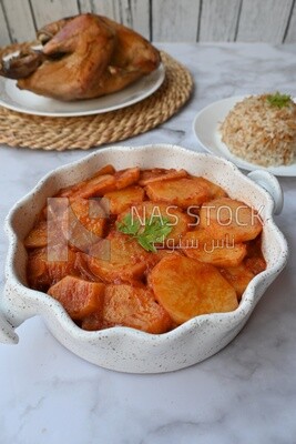 Potato tray sits beside a plate of rice and chicken