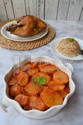 Potato tray sits beside a plate of rice and chicken