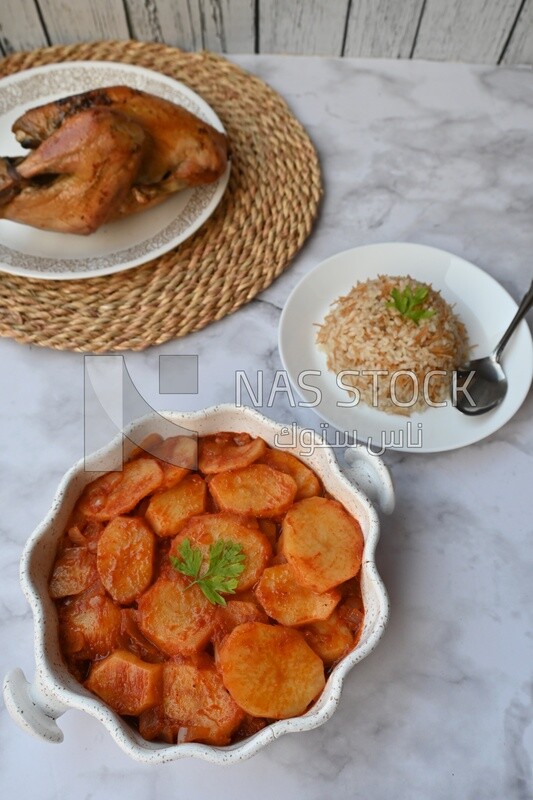 Potato tray sits beside a plate of rice and chicken