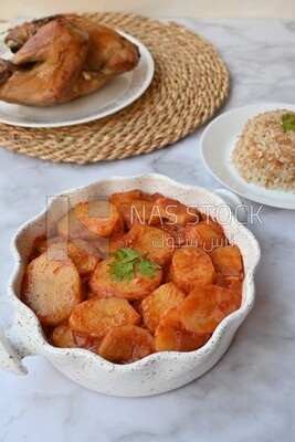 Potato tray sits beside a plate of rice and chicken
