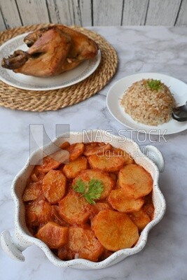 Potato tray sits beside a plate of rice and chicken