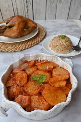 Potato tray sits beside a plate of rice and chicken