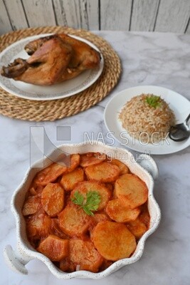 Potato tray sits beside a plate of rice and chicken