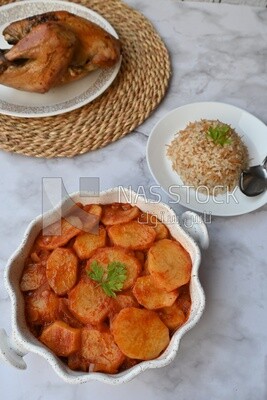 Potato tray sits beside a plate of rice and chicken