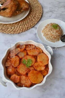Potato tray sits beside a plate of rice and chicken