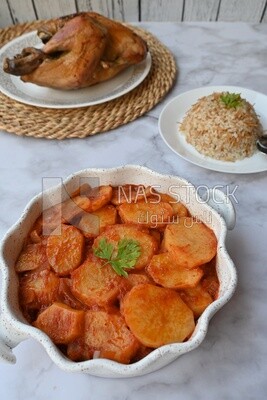 Potato tray sits beside a plate of rice and chicken