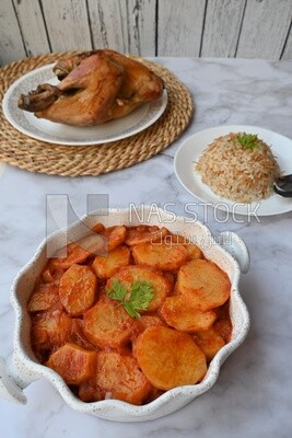 صينية بطاطس بجانب طبق ارز و دجاج