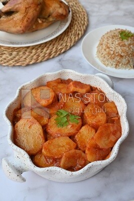 صينية بطاطس بجانب طبق ارز و دجاج