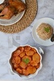 Potato tray sits beside a plate of rice and chicken