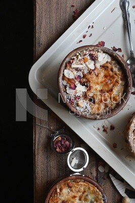 Top view of a plate of Umm Ali with nuts on it, cinnamon sticks, famous oriental Arabic sweets, bread and milk sweets