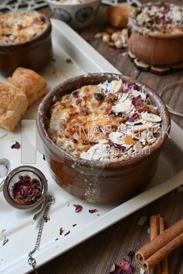 Plate of Umm Ali with nuts on it, cinnamon sticks, famous oriental Arabic sweets, bread and milk sweets