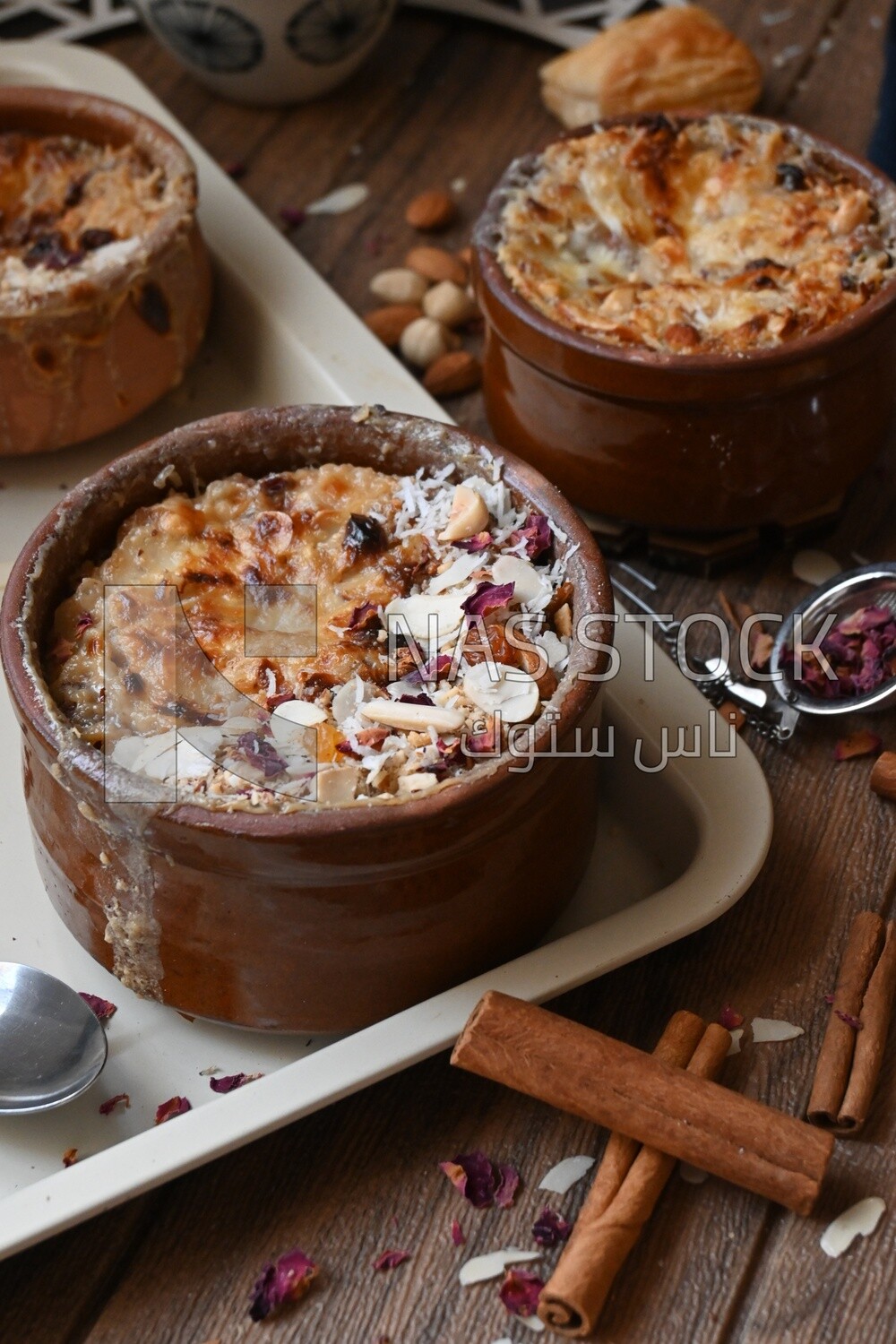 Plate of Umm Ali with nuts on it, cinnamon sticks, famous oriental Arabic sweets, bread and milk sweets
