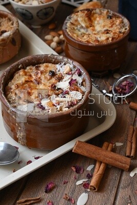 صورة مقربة لطبق أم علي وعليه المكسرات وأعواد القرفة والحلويات العربية الشرقية الشهيرة وحلويات الخبز والحليب