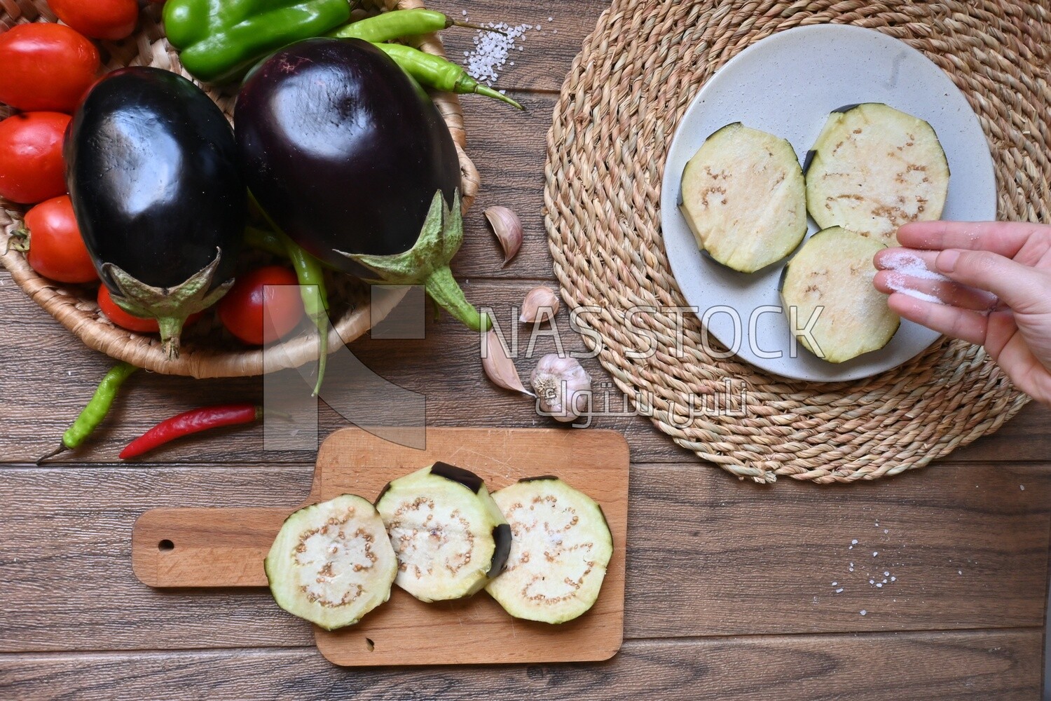 Hand puts the salt on the eggplant before cooking