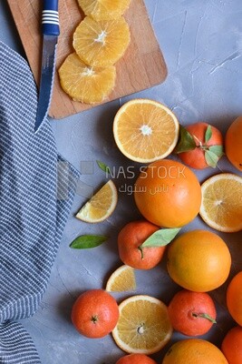 Oranges with a knife and orange slices on the table ​