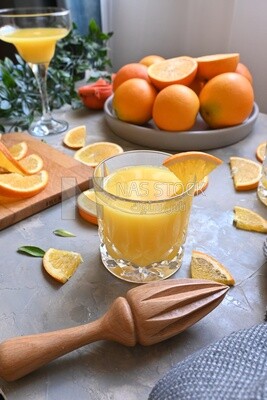 Glass of orange juice with a wooden citrus juicer