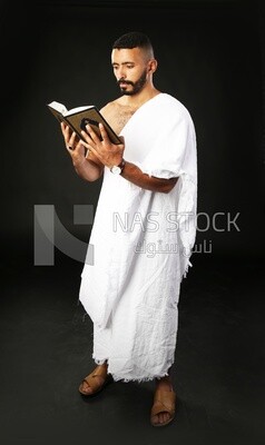 A man wearing an ihram dress prays