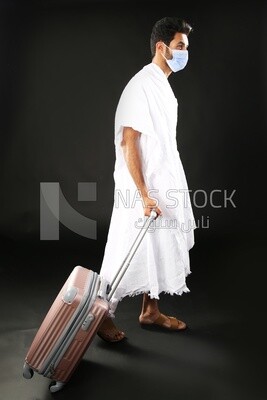 A man wearing an ihram dress with his luggage