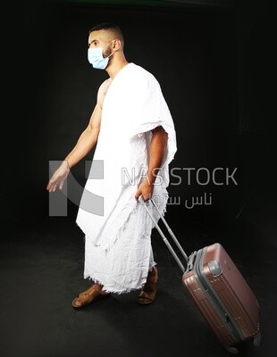 A man wearing an ihram dress with his luggage