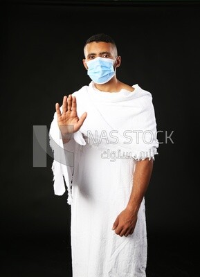 A man wearing an ihram dress pointing away
