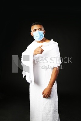 A man wearing an ihram dress pointing away