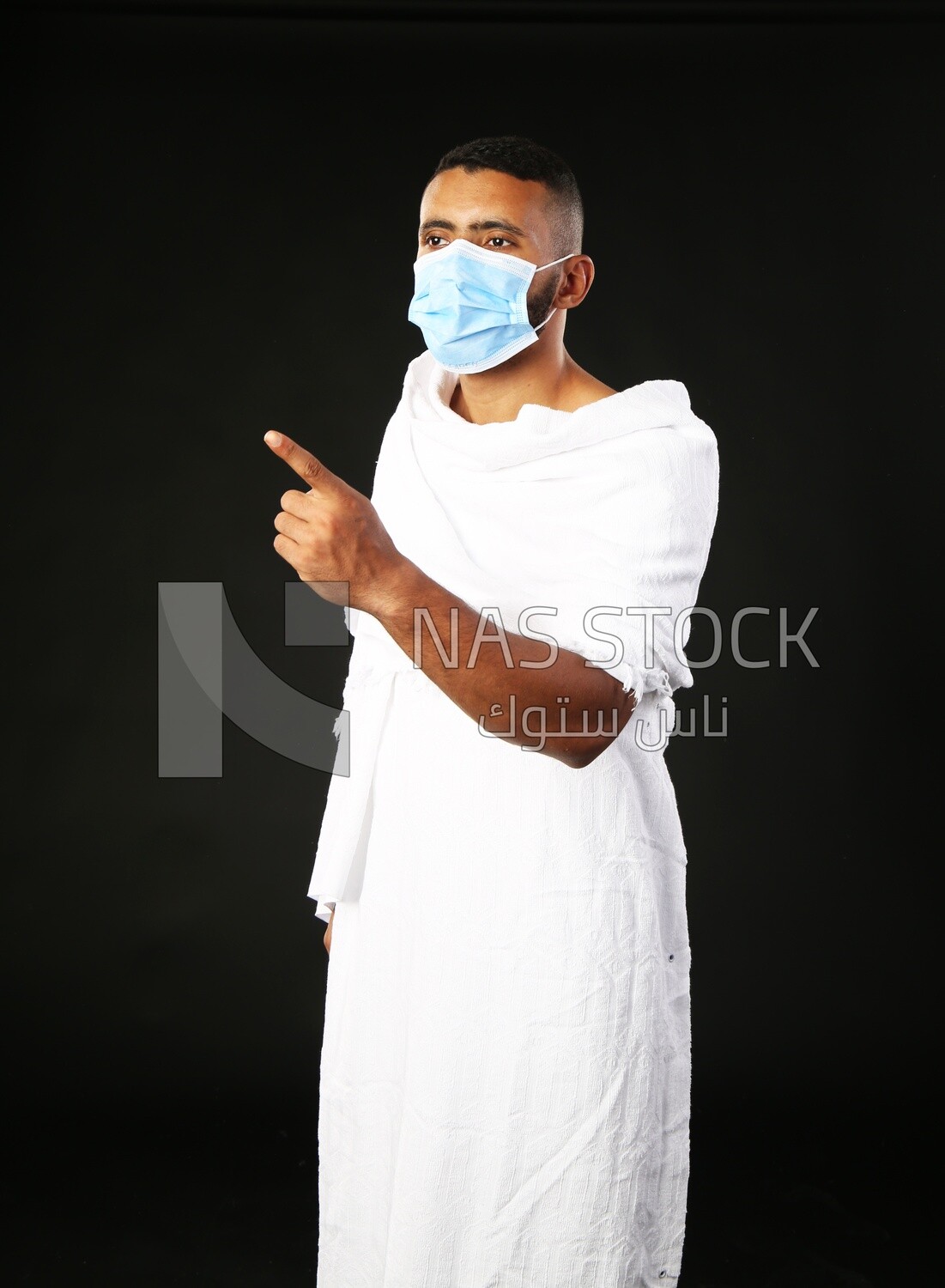 A man wearing an ihram dress pointing away