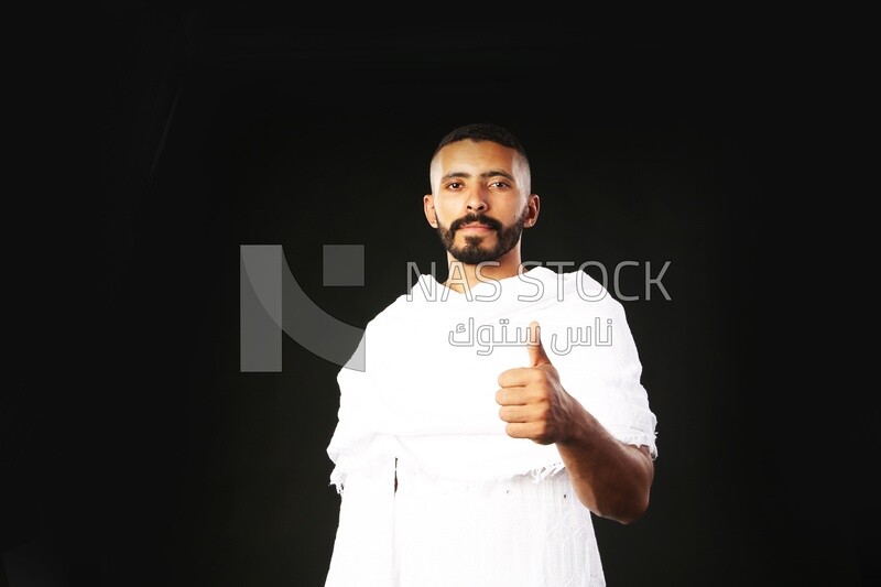 A man wearing an ihram dress doing an okay sign