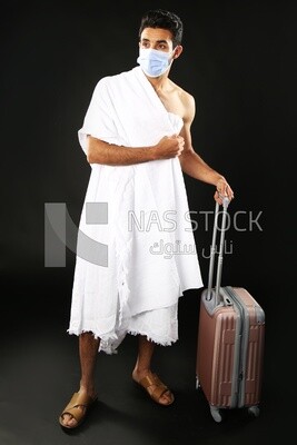 A man wearing an ihram dress with his luggage