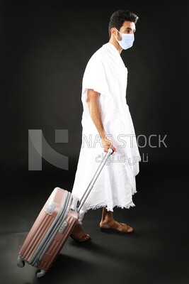 A man wearing an ihram dress with his luggage