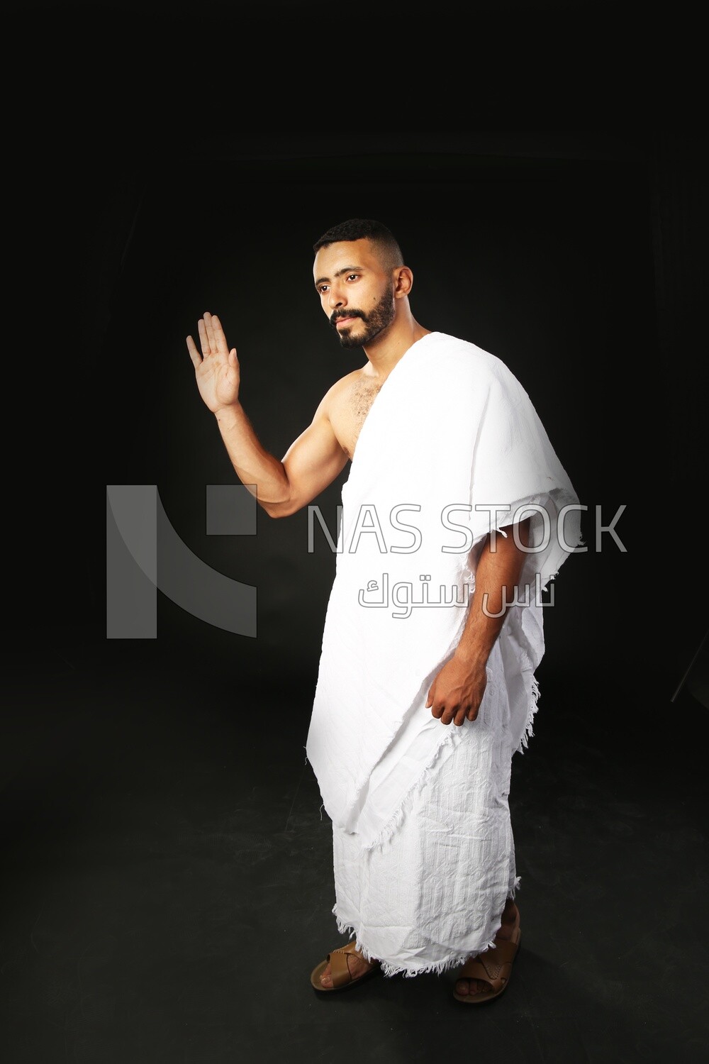 A man wearing an ihram dress and waving his hand ​