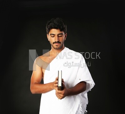 A man wearing an ihram dress prays