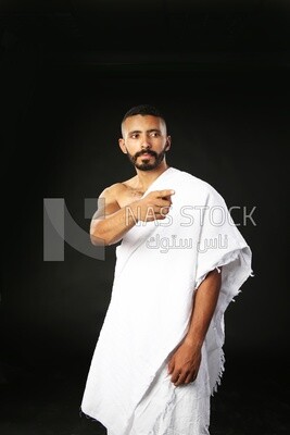 A man wearing an ihram dress pointing away