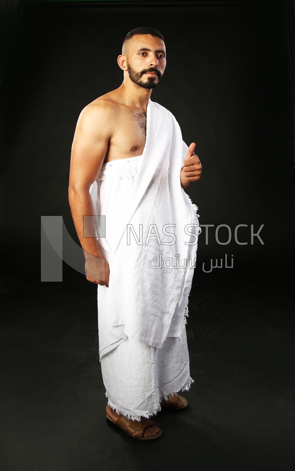 A man wearing an ihram dress doing an okay sign