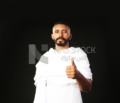 A man wearing an ihram dress doing an okay sign