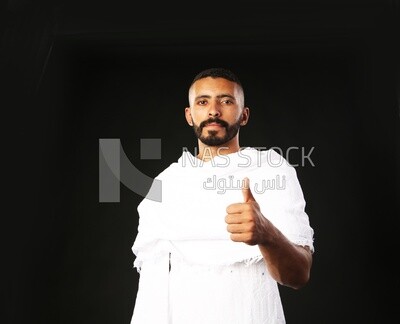 A man wearing an ihram dress doing an okay sign