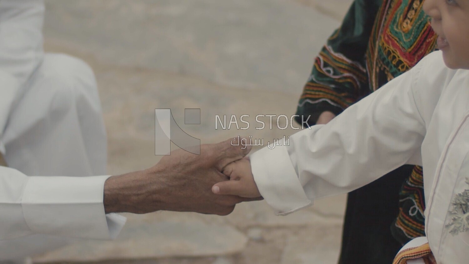 Child shakes hands with a big man, Saudi Arabia