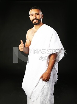 A man wearing an ihram dress doing an okay sign