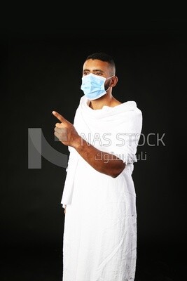 A man wearing an ihram dress pointing away