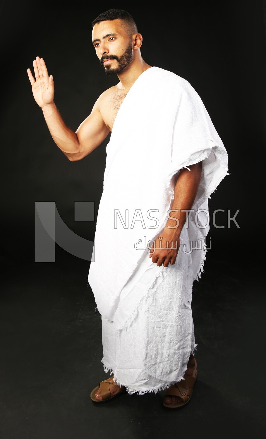 A man wearing an ihram dress and waving his hand ​