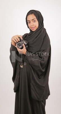 A woman with a hijab holding a camera