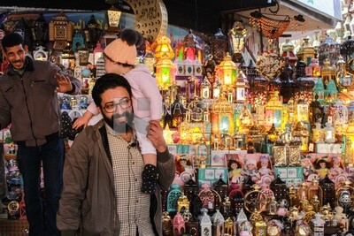 father buys a Ramadan lantern for his child and carries it on his shoulder in happiness
