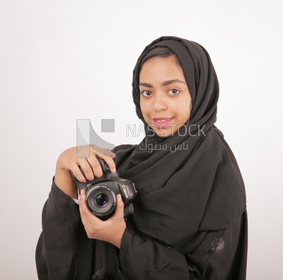 A woman with a hijab holding a camera